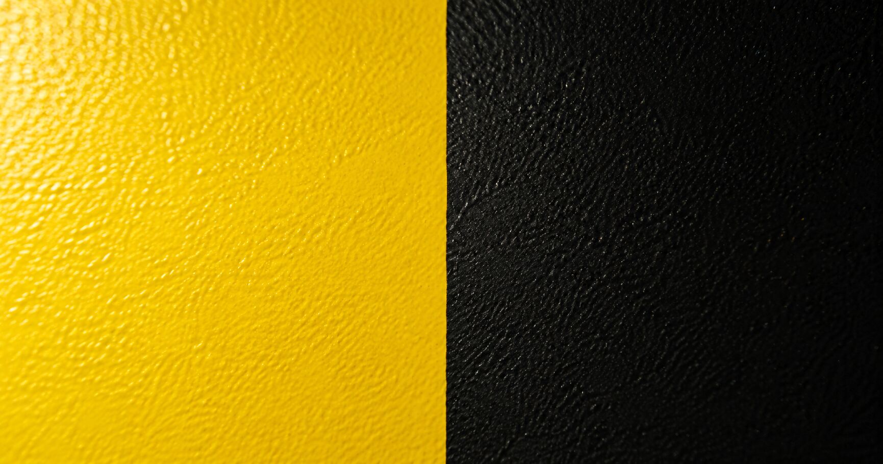 Close up of cured powder coat in yellow and black, showing the fine textured finish